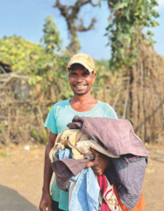 A villager smiling with an armful of donated clothes